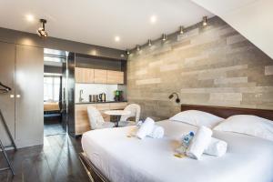 a bedroom with a large white bed and a kitchen at CMG - Suite Premium Tour Eiffel - 71 in Paris