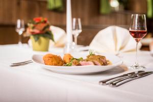 einen Teller mit Essen auf einem Tisch mit einem Glas Wein in der Unterkunft Brennereihotel Sponsel in Kirchehrenbach