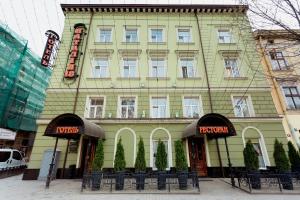 a yellow building with tables and chairs in front of it at Hotel Natalia 18 in Lviv