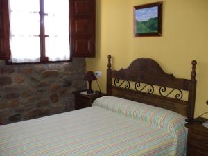 sypialnia z łóżkiem i kamienną ścianą w obiekcie Apartamentos La Corraliza w mieście Totero