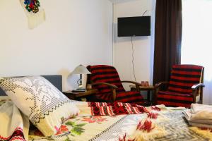 a bedroom with a bed with a blanket and two chairs at Lacrima Izei in Săcel