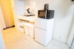 a kitchen with a microwave on top of a refrigerator at Shinjuku Partenza in Tokyo