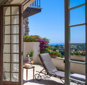 a chair on a balcony with a view at Château Le Cagnard in Cagnes-sur-Mer