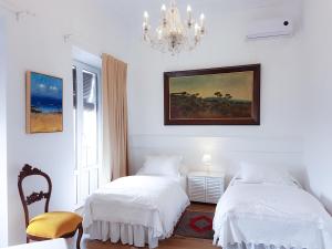 ヘレス・デ・ラ・フロンテーラにあるCasa Palacio Morla y Melgarejoの白いベッドルーム(ベッド2台、シャンデリア付)