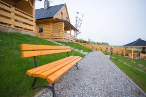 a wooden bench sitting in front of a building at Domki pod Kuźnią in Falsztyn