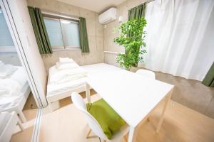 Cette petite chambre comprend une table et des chaises blanches. dans l'établissement Shinjuku Partenza, à Tokyo