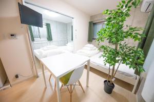 une chambre avec une table blanche et une plante en pot dans l'établissement Shinjuku Partenza, à Tokyo