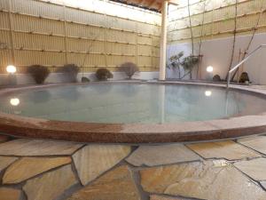 a large hot tub in a building with a stone floor at Nikko Station Hotel Classic in Nikko