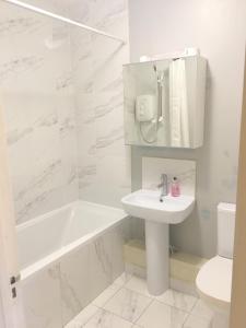 a white bathroom with a sink and a tub and a toilet at Cozy apartment next to Dublin Castle in Dublin