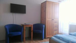 sypialnia z 2 niebieskimi krzesłami i telewizorem w obiekcie Penzión Aqua w Liptowskim Mikulaszu