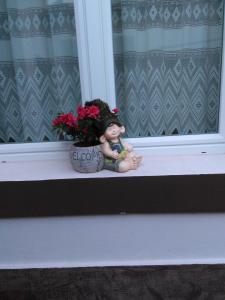 una muñeca sentada en un alféizar junto a una maceta en Mama Brasov en Brasov