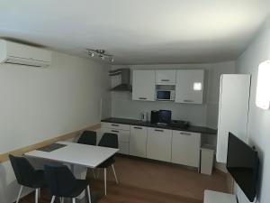 a kitchen with white cabinets and a table and chairs at Top Line Apartments in Piran