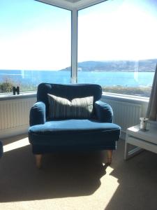 a blue chair sitting in front of a large window at Dalriada Crescent in Cushendall