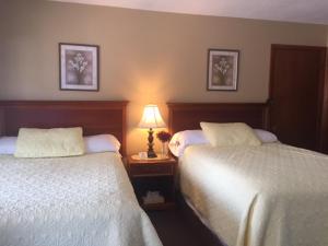 una habitación de hotel con 2 camas y una lámpara en Milford Motel On the River en Milford
