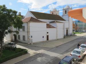 a white building with a church in the background at Alojamento Cesarini in Montijo