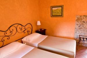 two beds in a room with orange walls at Locanda la Casetta in Angera