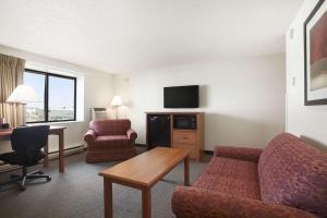 a hotel room with a couch and a table and a desk at Super 8 by Wyndham Williston ND in Williston