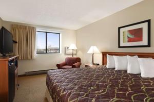 um quarto de hotel com uma cama e uma televisão em Super 8 by Wyndham Williston ND em Williston