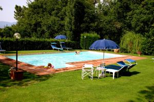 a pool with chairs and umbrellas and people in it at Le Giunchete in Cavriglia