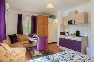 a kitchen and living room with a table and purple chairs at Apartment Monica in Ližnjan