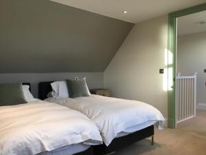 1 dormitorio con 1 cama con sábanas blancas y almohadas verdes en Dunvegan Castle Keepers Cottage en Dunvegan