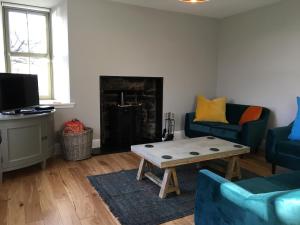 a living room with two blue couches and a coffee table at Dunvegan Castle Keepers Cottage in Dunvegan