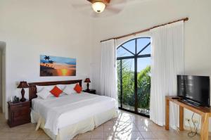 a bedroom with a bed and a tv and a window at Stay in Tamarindo Condominiums in Tamarindo