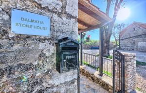a stone wall with a sign on a stone house at Dalmatia Stone House - heated pool in Biorine