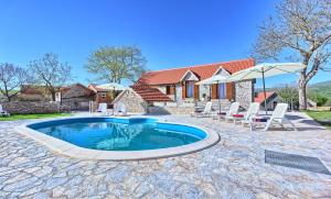 a swimming pool with chairs and a house at Dalmatia Stone House - heated pool in Biorine