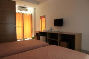 um quarto com 2 camas e uma secretária com uma televisão em The Ocean Residence em Nakhon Ratchasima