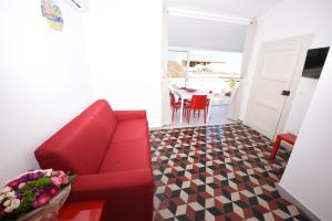 a living room with a red couch and a table at Terrazza in Palazzo Taormina in Castellammare del Golfo