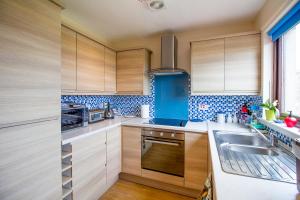 una cocina con armarios de madera y azulejos azules en las paredes. en Beach House Walk - Crail - Home from Home, en Crail