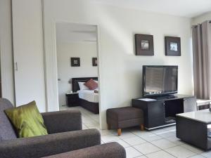 a living room with a couch and a television at Jadran Motel & El Jays Holiday Lodge in Gold Coast