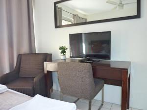 a living room with a tv and a chair at Jadran Motel & El Jays Holiday Lodge in Gold Coast