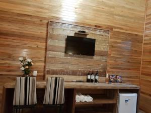 a room with a wooden wall with a table with bottles of wine at Pousada Vila dos Butias in Urubici +173 photos