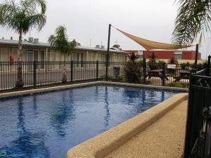 a swimming pool in front of a building with a fence at Overlander Hotel Motel in Shepparton