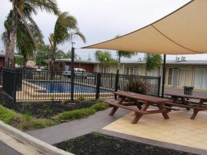 a picnic table with an umbrella next to a pool at Overlander Hotel Motel in Shepparton