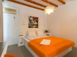 a white bedroom with an orange bed and a chandelier at Giannoulis Hotel in Adamantas