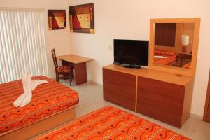 グアダラハラにあるホテル レアル サポパンのテレビ、ベッド、鏡が備わるホテルルームです。