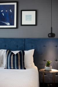 a bedroom with a bed with a blue headboard and a table at Mrs Banks Hotel in Sydney