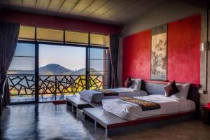 a bedroom with two beds and a large window at Wang Put Tan Boutique House in Mae Salong