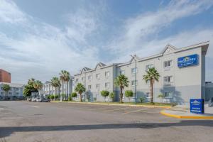 un grand bâtiment blanc avec des palmiers dans un parking dans l'établissement Microtel Inn & Suites by Wyndham Culiacán, à Culiacán