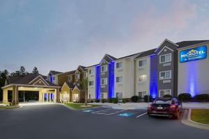 a hotel with a car parked in a parking lot at Microtel Inn & Suites by Wyndham Walterboro in Walterboro