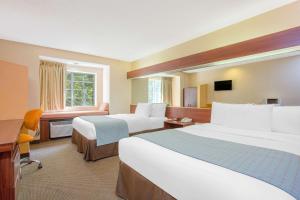 una camera d'albergo con due letti e una scrivania di Microtel Inn & Suites by Wyndham Kannapolis/Concord a Kannapolis