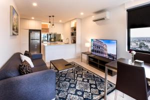 Una sala de estar con un sofá y una mesa con televisión. en Spencer Street Apartments, en Melbourne
