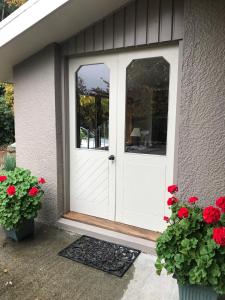 uma porta branca numa casa com flores vermelhas em McIvor Lodge em Invercargill