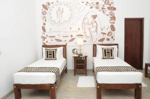 two twin beds in a room with a mural at Jaffna Heritage Villa in Jaffna