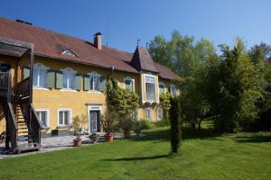 a large yellow house with a tree in the yard at Schloss Pesenbach Chalet im Freizeitland Feldkirchen an der Donau in Feldkirchen an der Donau