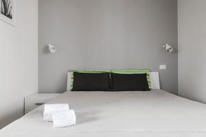 a white bed with black pillows in a bedroom at Addisa Locazione Breve in Castellammare del Golfo