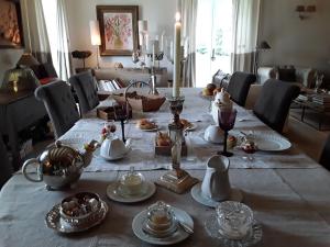 a dining room table with a table set with dishes and candles at Le Relais du Haras in Champagné-Saint-Hilaire
